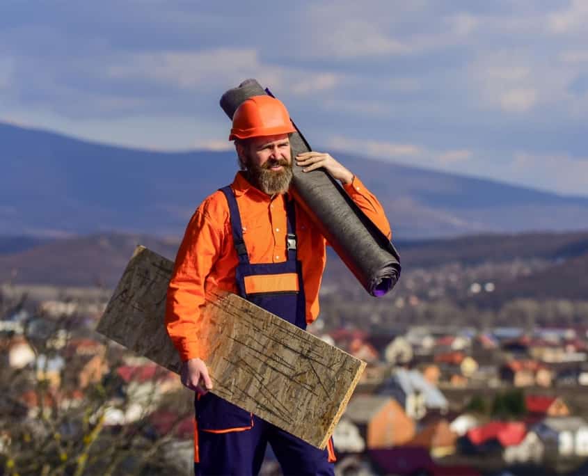Side view of a man holding roofing materials