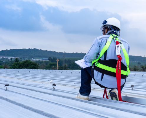 Man wearing full safety body harness working on roof top