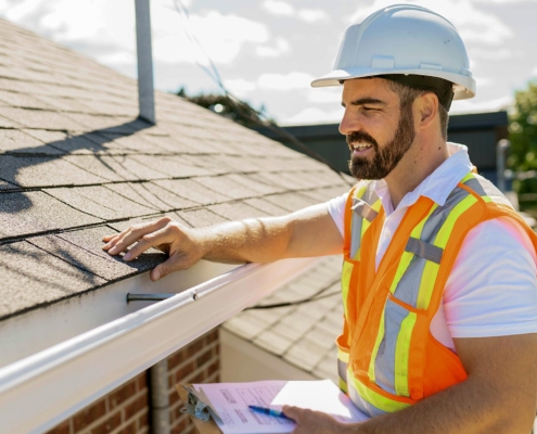 Worker with clipboard inspecting residential roof