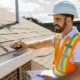 Worker with clipboard inspecting residential roof